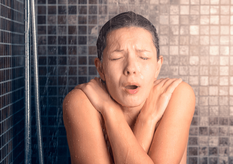 Woman in cold shower shivering as there is no hot water