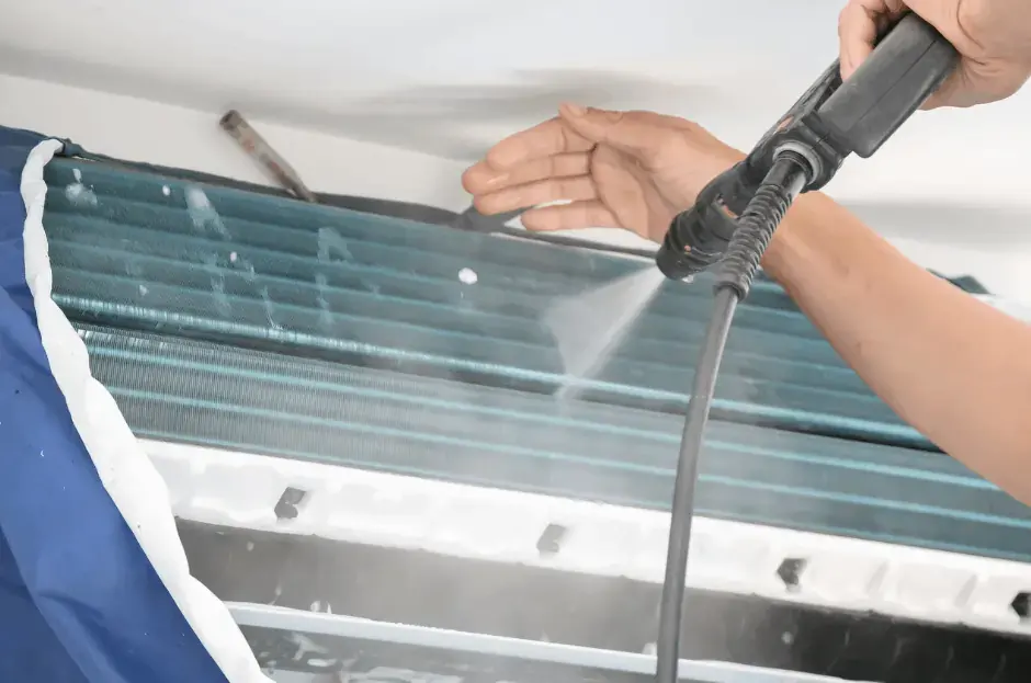 Technician cleaning an air conditioning unit