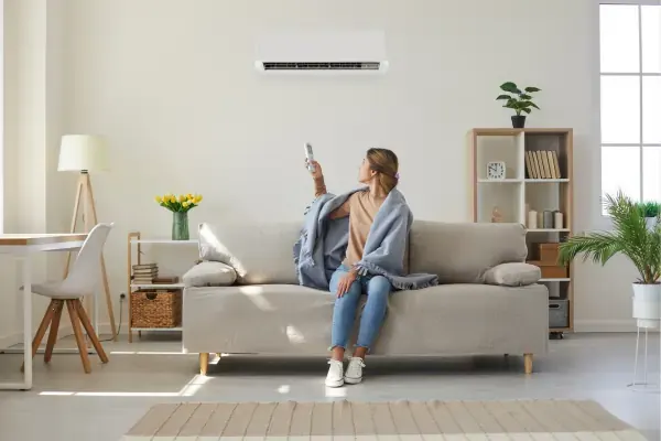 Woman sitting under AC with blanket over shoulders
