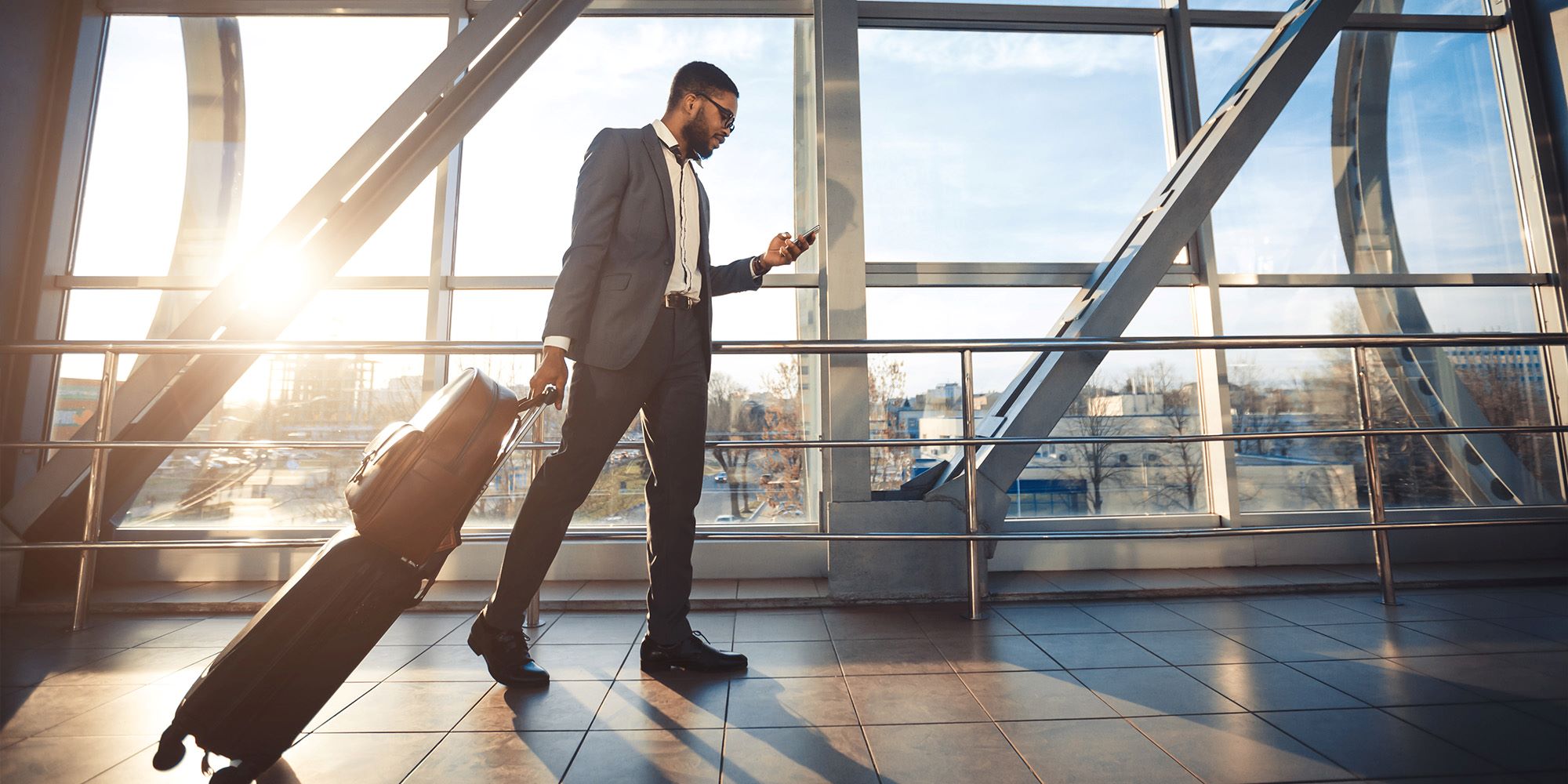 Businessman Using Mobile Phone Walking In Airport, Panorama, Side-View