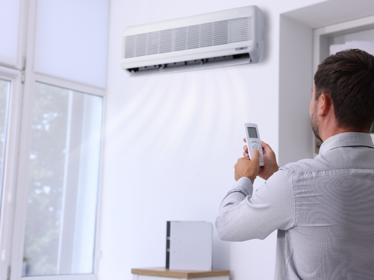 Man adjusting temperature of a faulty split system air conditioner