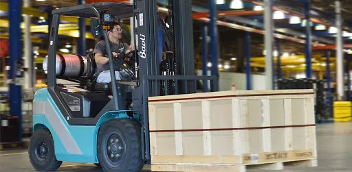 Technician operating forklift to lift heavy equipment