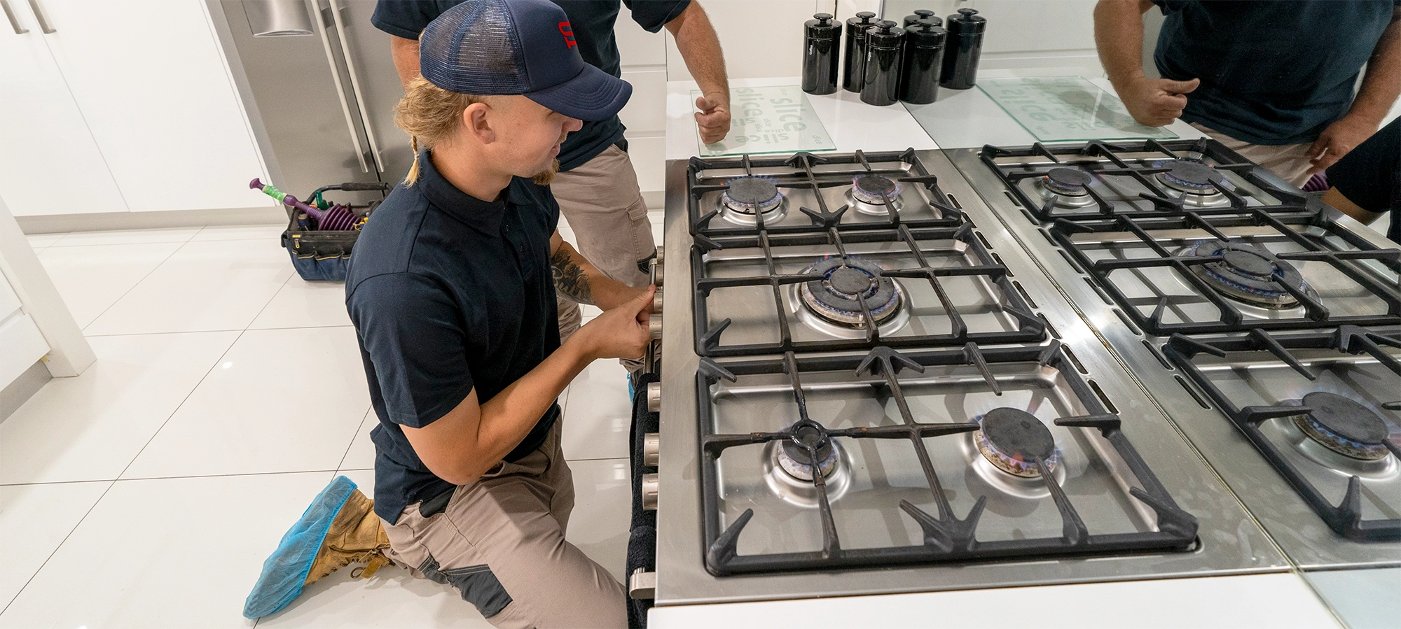 Gas plumber installing new gas stove with gas oven and gas cooktop. Gas fitter is testing the new gas appliance to check optimal performance and ensure gas safety