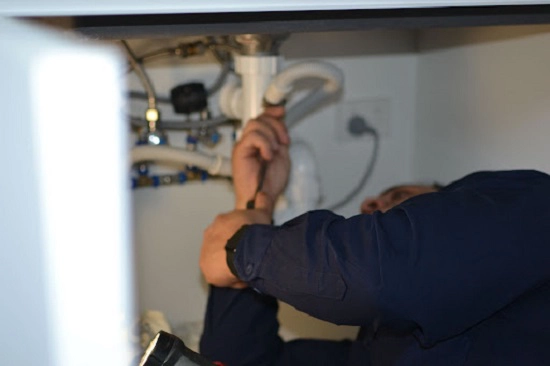 sink drain issue in home plumber laying under sink pipes