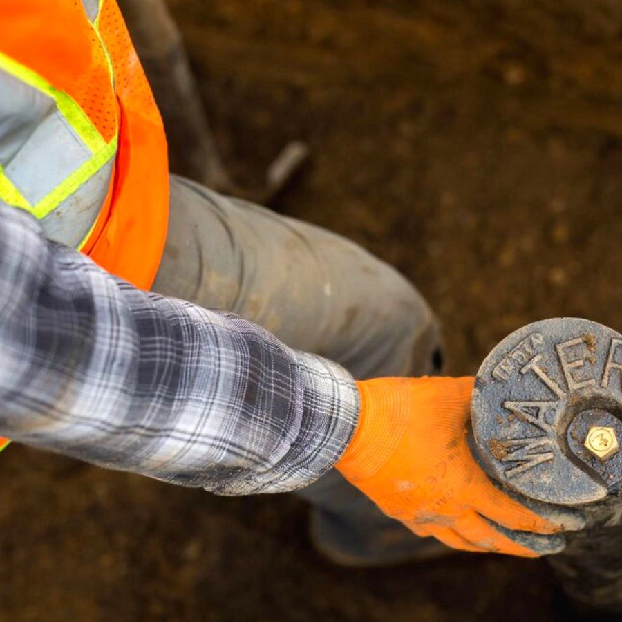Plumber Holding Water Pipe Underground