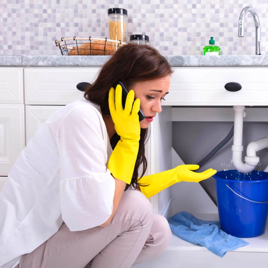 Woman Calling Emergency Plumber Kitchen Sink Pipe Leak