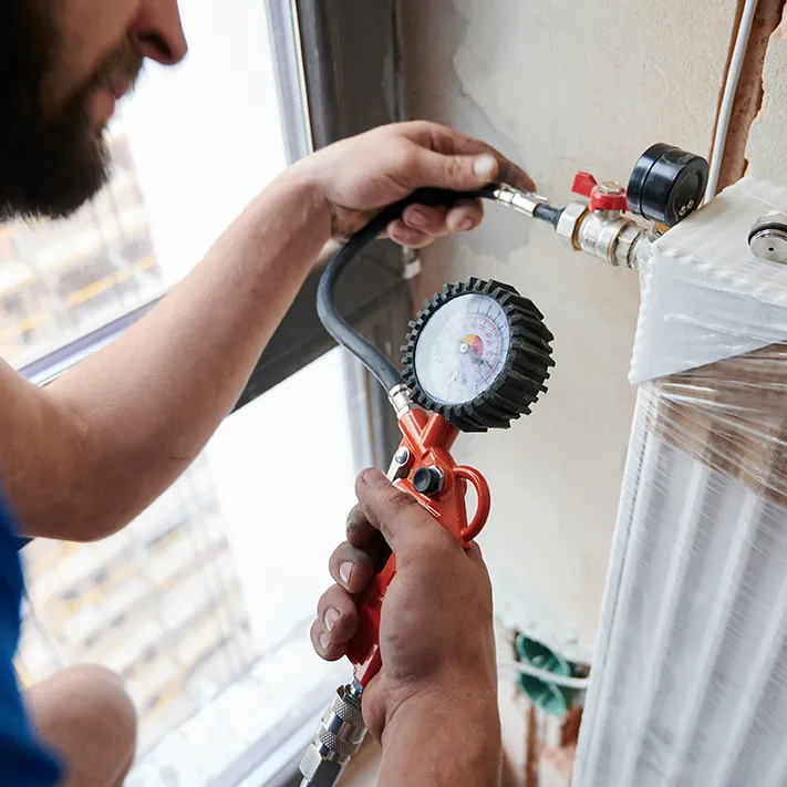 Gas Fitter using an air compressor to check gas tightness of gas hot water system and gas heating system