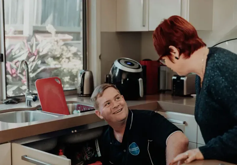 Evermore Plumbing & Gas specialist gas fitter smiling whilst checking for leaks in a kitchen