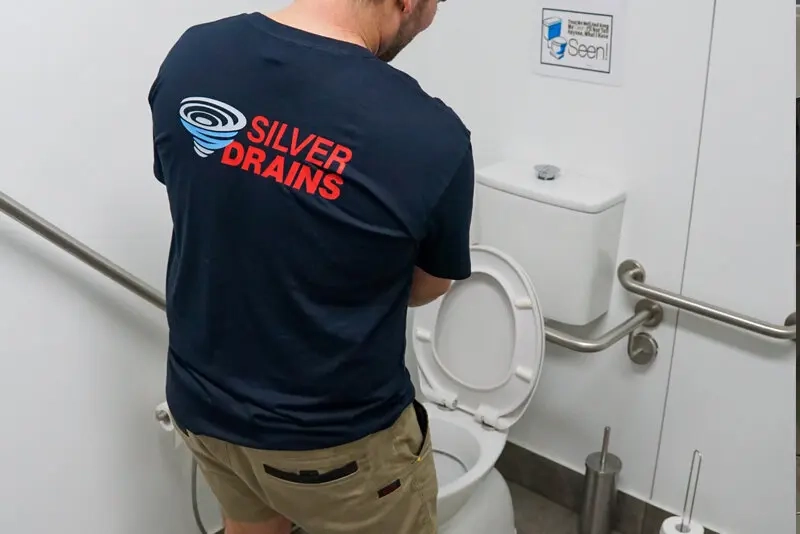 blocked toilet, plumber using plunger