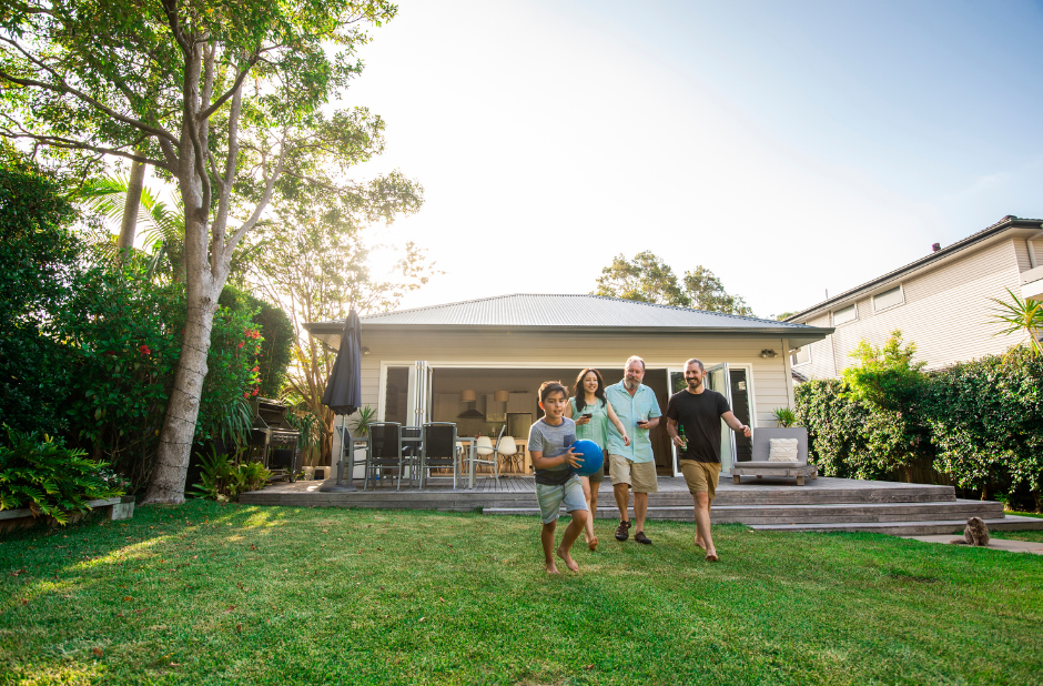 Backyard garden with great drainage system as the grass is all dry and no pooling water. shows a family enjoying playing with a ball in their dry backyard