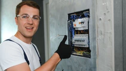 Electrician giving thumbs up by switchboard