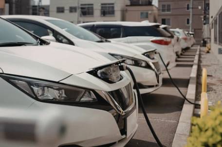 Fleet of electric vehicles plugged in and charging in the car park of a business whilst the ev owners work