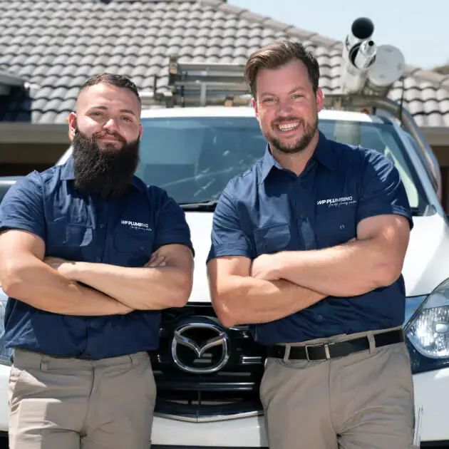 Two of our qualified plumbers smiling in front of their work van