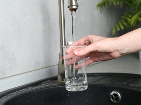 Women pours herself a glass of water from an under sink water filter system