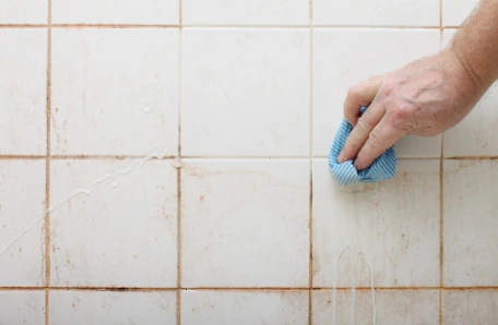 Cleaning bathroom tiles and grout with a cloth and cleaning products