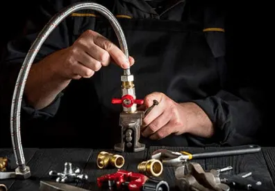 Master plumber connecting brass fittings to a plumbing hose during gas fitting work