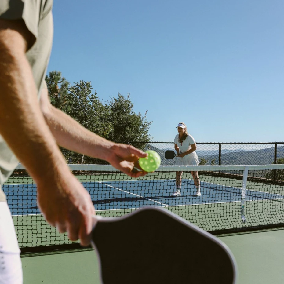 Close-up of pickleball paddles being held court-side